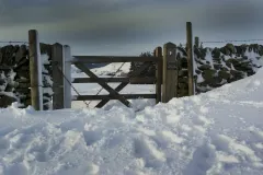 Snowdrift around a gate and dry stone wall